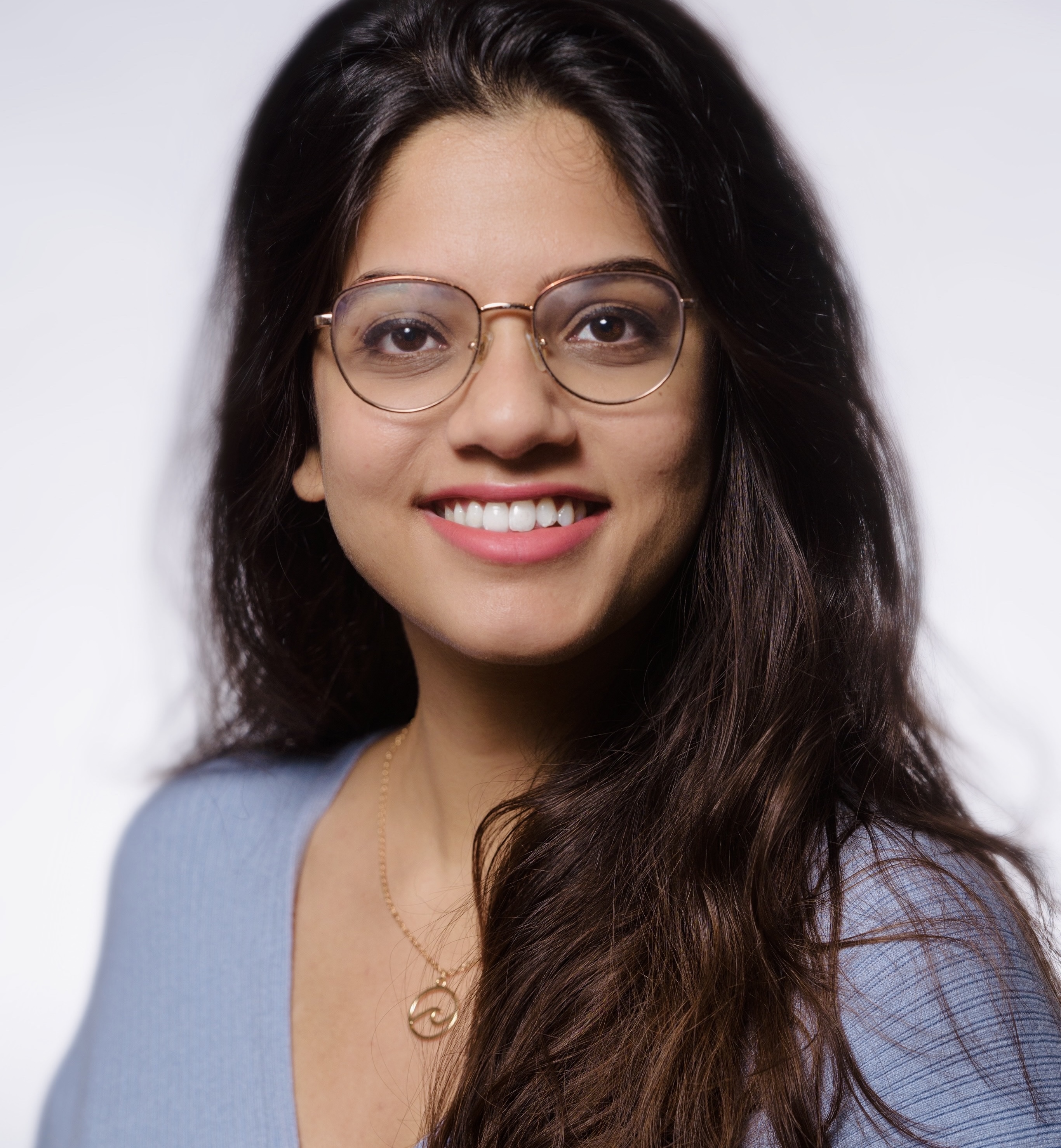 Picture of Deepti: Brown woman with hair down, in a blue sweater dress